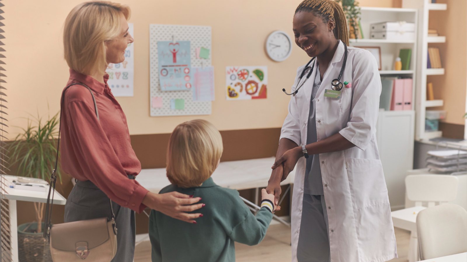 A clinician greets a parent and child in clinic